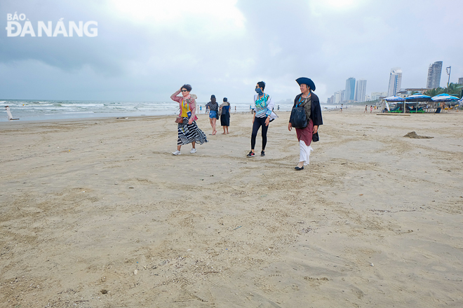 Du khách tham quan bãi biển Phạm Văn Đồng sau khi khu vực này được dọn dẹp sạch sẽ.