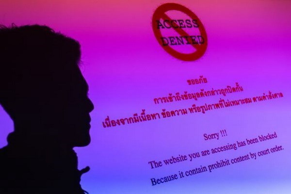 A man is silhouetted onto an electronic screen displaying prohibited website in Bangkok, Thailand (Source: Reuters)