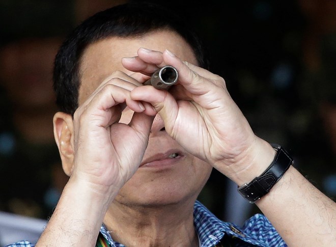 Philippine President Rodrigo Duterte looks through a broken muzzle of a rifle after hundreds of guns and weapons were confiscated during a pro-Islamic State group siege in Marawi last year.(Source: https://asia.nikkei.com)