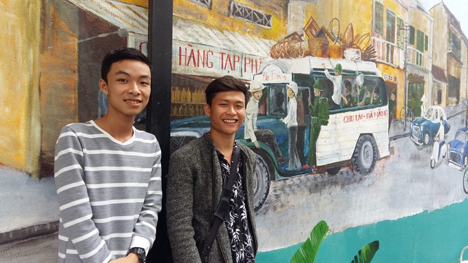 Phạm Văn Thiện (right) and Nguyễn Xuân Hậu pose in front of their mural at a cafe in Đà Nẵng. — VNS Photo Công Thành Read more at http://vietnamnews.vn/english-through-the-news/481858/walls-that-tell-stories.html#33jwMA75rP64rpQg.99