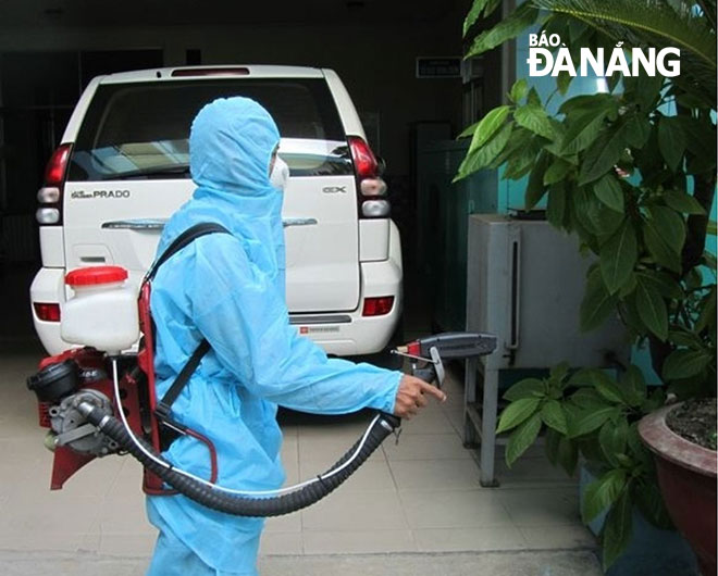 A medical worker spraying anti-mosquito chemicals at a family 