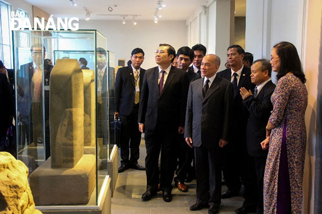 King of Cambodia Norodom Sihamoni (centre) and Chairman Tho (2nd left) listening to an introduction to artifacts displayed in the museum.