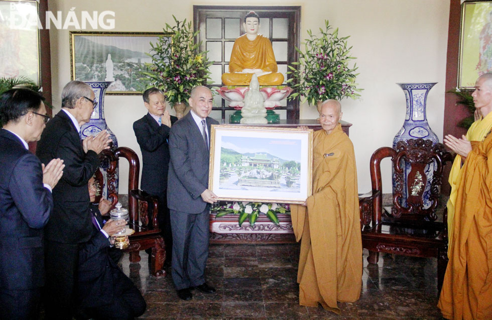 A representative of Buddhist dignitaries presenting a picture featuring an overview of the pagoda to King Norodom Sihamoni (left)