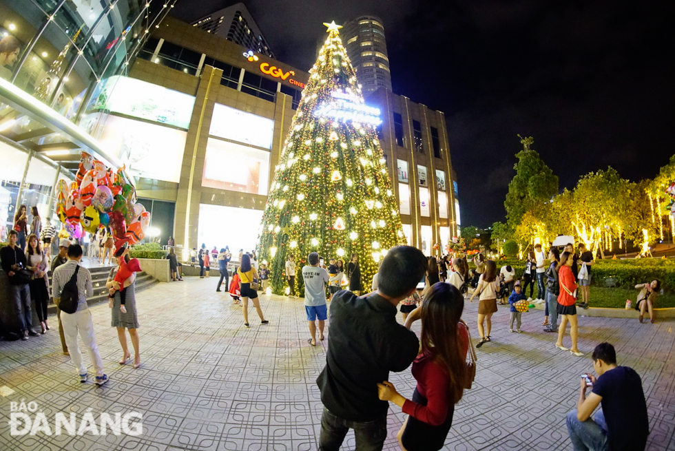 Dozens of local residents and tourists having their photos taken with a giant Christmas tree in front of the main entrance to the Vincom Ngo Quyen Trade Centre