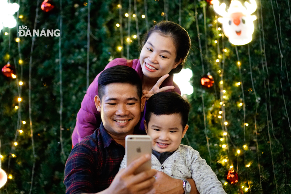  A family posing for a group photo besides a giant the Christmas tree