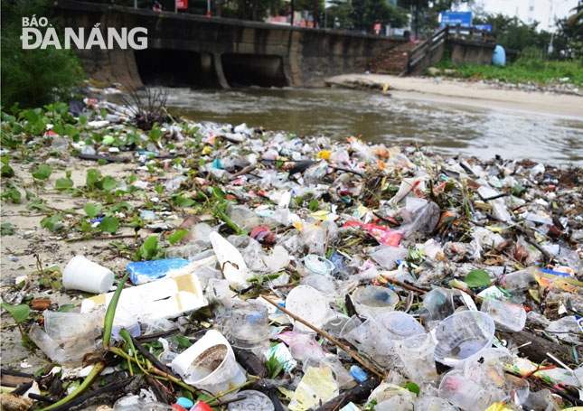 A large amount of plastic waste seen along the sides of the drain outlet opposite to Ton That Dam Street