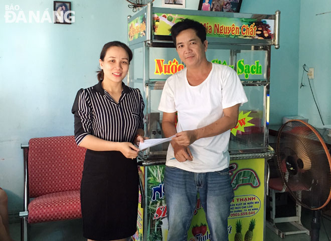 Đại diện Phòng LĐ-TB&XH quận Ngũ Hành Sơn (trái) trao xe nước mía giúp một hộ nghèo ở phường Hòa Hải có phương kế sinh nhai ổn định cuộc sống.