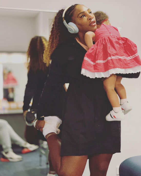 Serena Williams vừa ôm con gái Olympia vừa khởi động trước trận đấu ở Hopman Cup. 