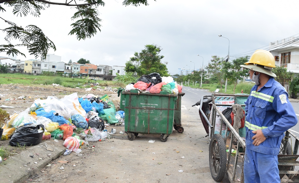 Một công nhân Xí nghiệp Môi trường Sơn Trà bất lực nhìn rác tồn đọng và chờ đợi xe đến thu gom rác.