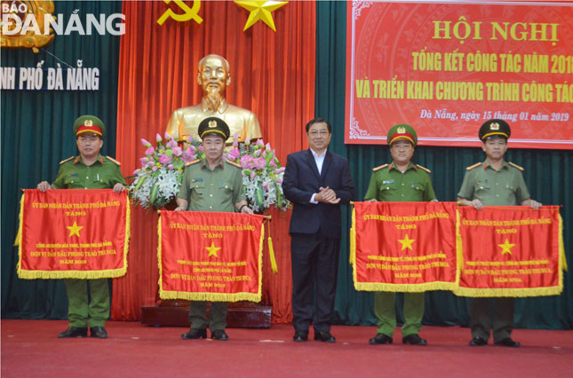 Chủ tịch UBND thành phố Huỳnh Đức Thơ tặng cờ thi đua xuất sắc của UBND thành phố cho các tập thể thuộc Công an thành phố Đà Nẵng. Ảnh: NGỌC PHÚ