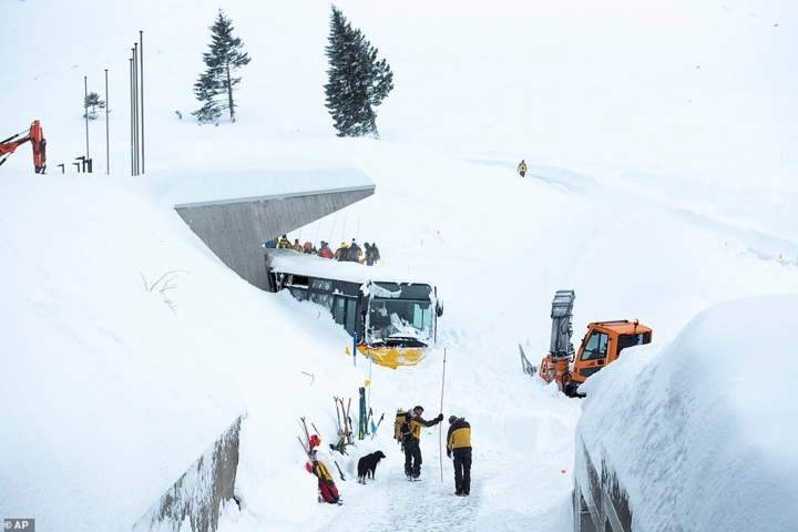 Các nhân viên cứu hộ đang nỗ lực để đưa chiếc xe buýt bị kẹt trong tuyết ra ngoài ở Schwaegalp, Thụy Sĩ. Ảnh: AP