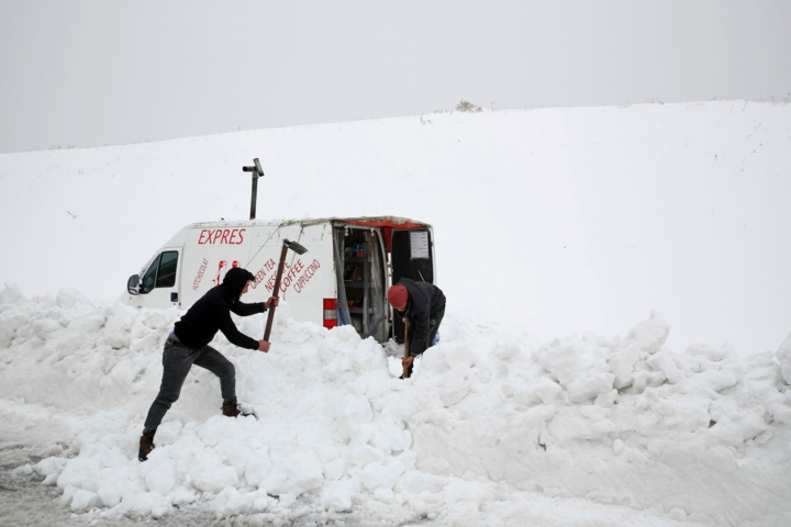 Hai người đàn ông đang dọn dẹp tuyết để chiếc xe tải bán các loại đồ uống nóng của họ có thể di chuyển được trên một con đường ở làng Mdeirij, Syria. Ảnh: AP