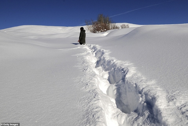 Một người dân địa phương đi bộ qua lớp tuyết rơi dày đặc ở làng Disbudak thuộc tỉnh Bingol, Thổ Nhĩ Kỳ