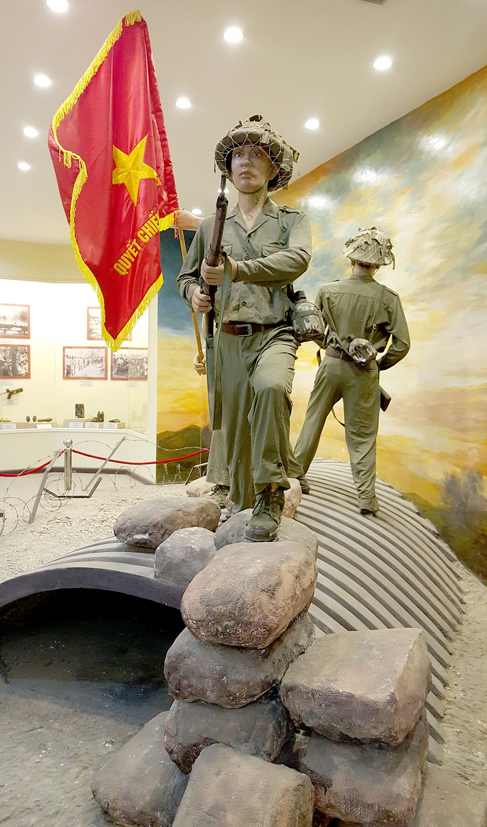 Vietnamese soldiers standing on the bunker of Christian de Castries with the flag of victory.