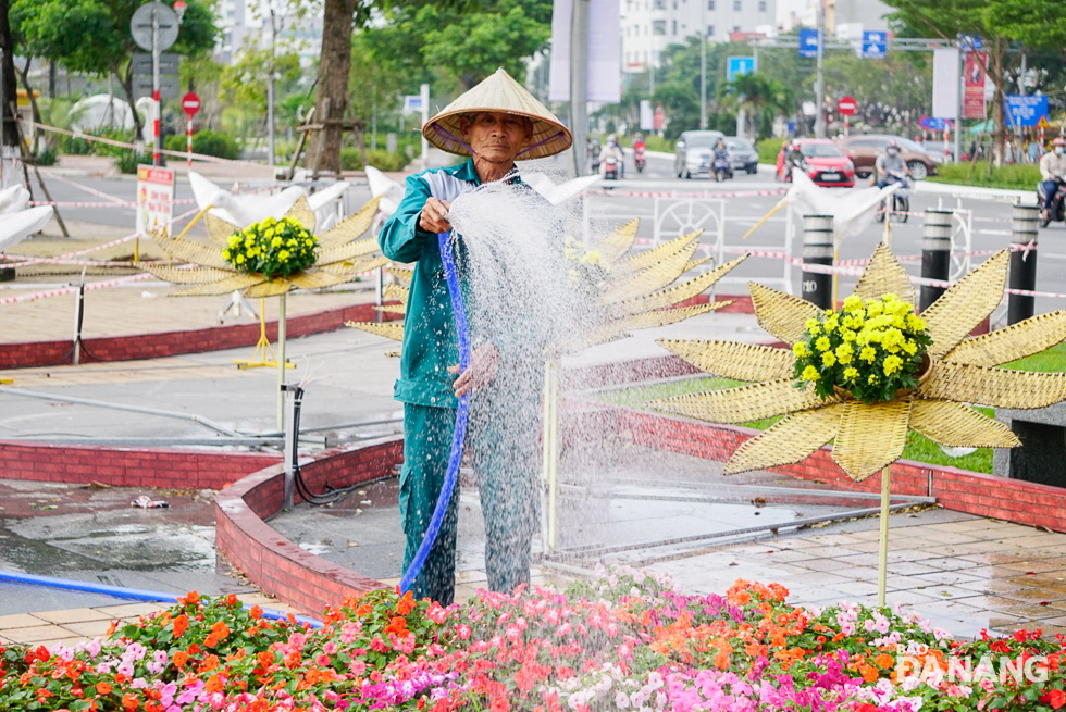 Workers are seen taking care of flowers along the street