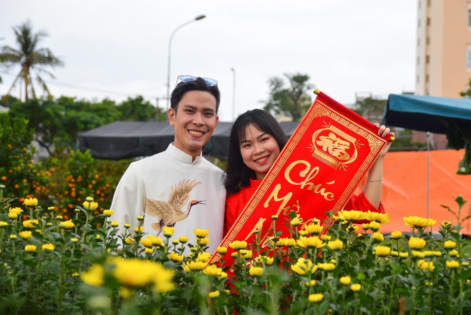 Young people posing for souvenir photos with well-trimmed yellow chrysanthemums.