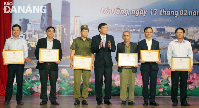 Phó Chủ tịch UBND thành phố Lê Trung Chinh (thứ 4, từ trái) tặng bằng khen của UBND thành phố cho các tập thể có thành tích xuất sắc trong phong trào Toàn dân bảo vệ an ninh Tổ quốc năm 2018. 				         Ảnh: THU THẢO