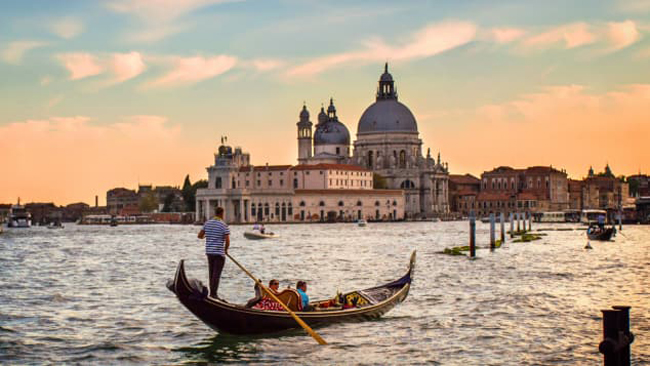 Gondoliers (người chèo thuyền) lúc hoàng hôn trên sông Venice, Ý