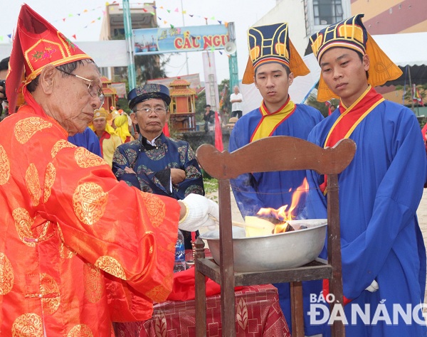 A senior male citizen burning paper offerings to the Gods of the Sea and the Whale