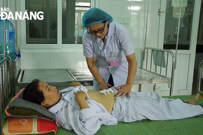 Thượng tá, bác sĩ Lê Thị Ngọc Tâm đang kiểm tra vết mổ của bệnh nhân Phan Thị  Mười.