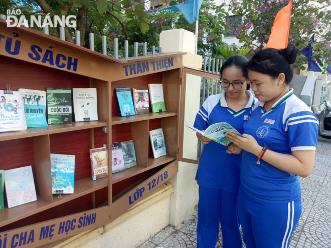 Pupils from the Tran Phu Senior High School eagerly reading books chosen from in sidewalk closets placed in front of the school gate