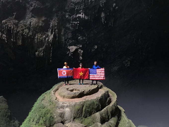 Visitors at the En Cave in Quang Binh Province with flags of the DPRK, USA and Viet Nam.