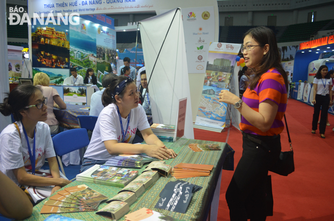 A visitor learning about tourism products at a pavilion hosted by Da Nang, Thua Thien Hue and Quang Nam in a fair.