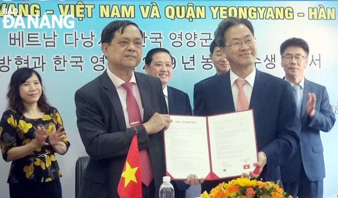 Ông Đặng Thương - Chủ tịch UBND huyện Hòa Vang (trái) và ông Oh DoChang - Quận trưởng quận Yeongyang (Hàn Quốc) ký kết bản hợp tác tu nghiệp sinh nông nghiệp.