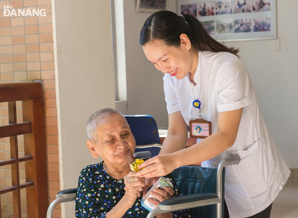 Chị Thanh Huyền, nhân viên Trung tâm Phụng dưỡng người có công thành phố Đà Nẵng phục vụ bữa ăn giữa giờ cho một cụ già ở trung tâm. Ảnh: XUÂN SƠN