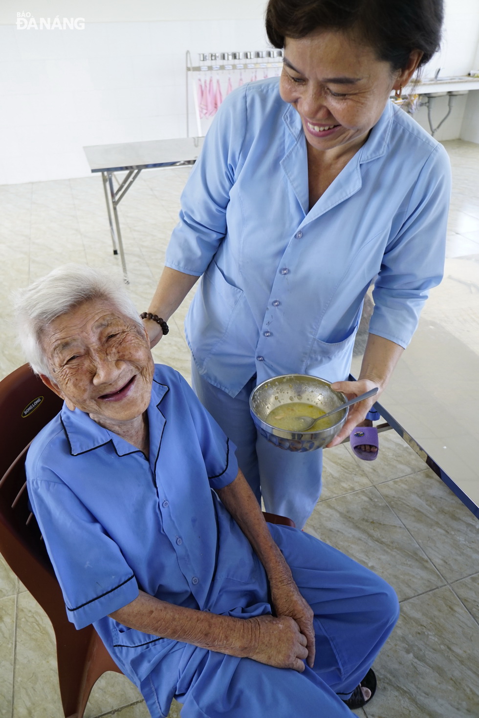 An elderly female citizen is being fed by a staff member