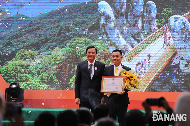 Municipal PC Vice Chairman Tran Van Mien (left) awarding the Certificate of Merit from the municipal PC Chairman to the Ba Na Service Cable Car JSC