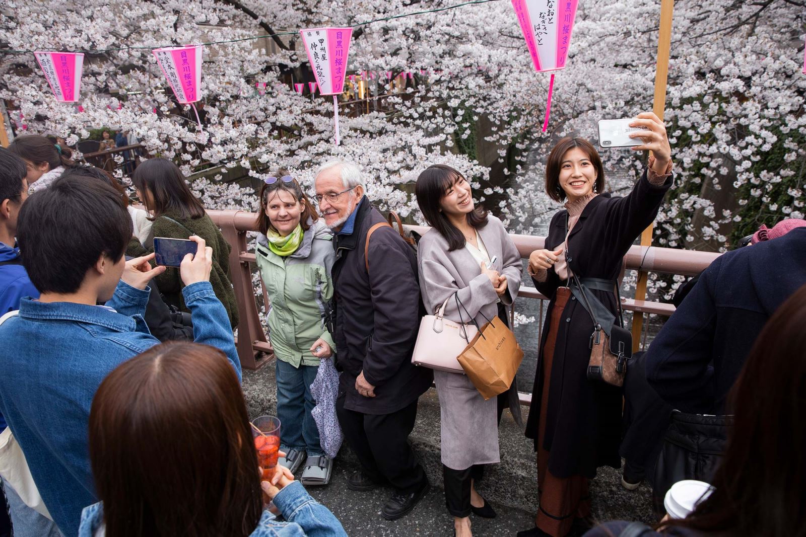Du khách chụp ảnh với hoa anh đào bên sông Meguro ở Tokyo. Ảnh: Bloomberg