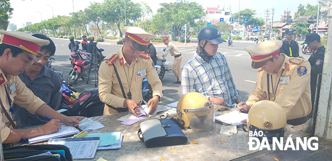 CSGT lập biên bản xử phạt vi phạm hành chính người điều khiển xe máy vi phạm Luật giao thông đường bộ. Ảnh: NGỌC PHÚ