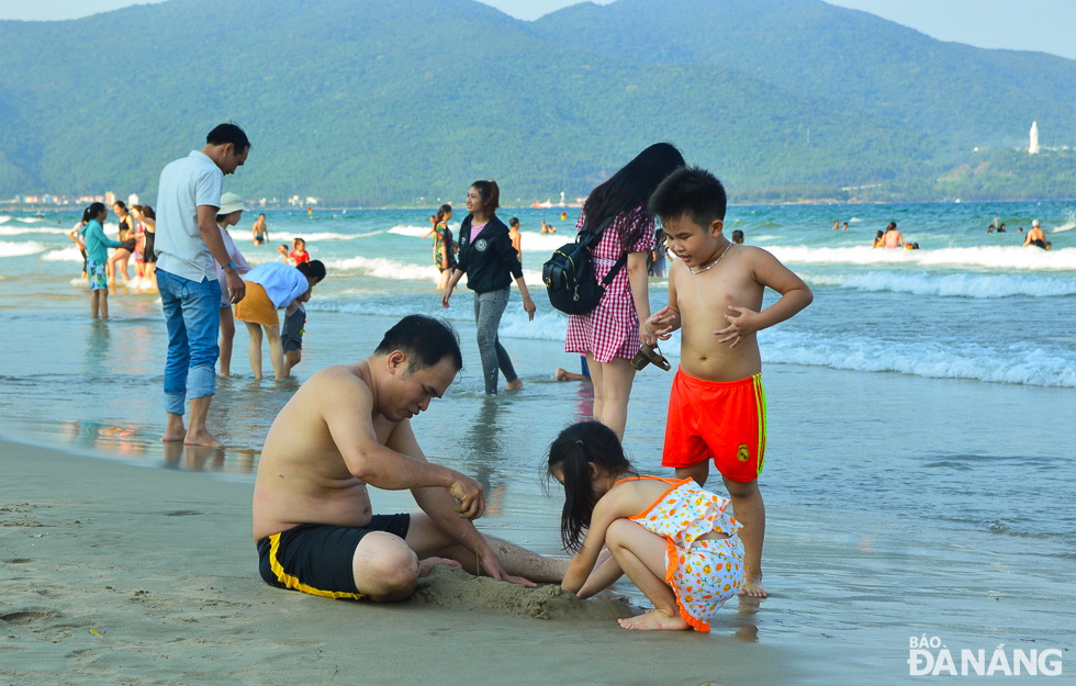  A lot of both adults and kids together creating sand sculptures