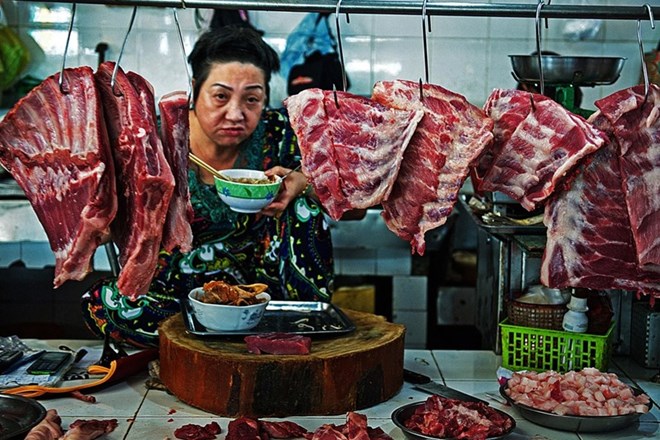 The photo captures a butcher woman having breakfast at Ben Thanh market in Ho Chi Minh City (Source: https://laodong.vn)