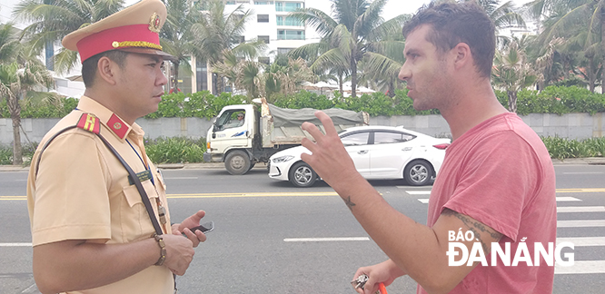 A traffic police officer explaining Viet Nam’s road traffic laws in English to a foreigner