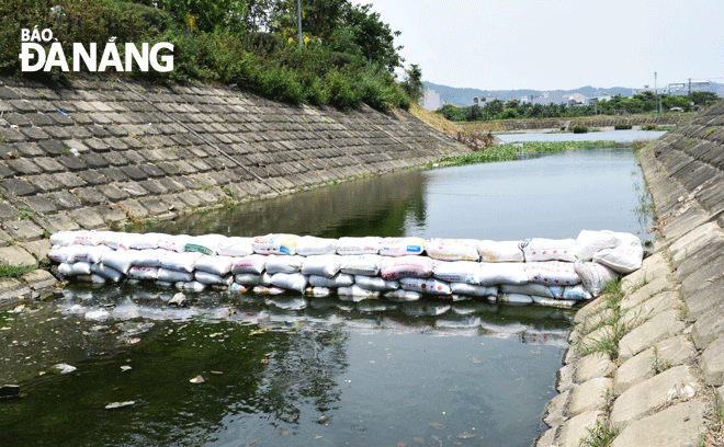 Công ty Thoát nước và Xử lý nước thải Đà Nẵng đắp đập tạm bằng bao cát tại hồ Trung Nghĩa để bảo đảm môi trường, ngăn nước thải chưa được thu gom chảy về sông Phú Lộc. 															       Ảnh: HOÀNG HIỆP