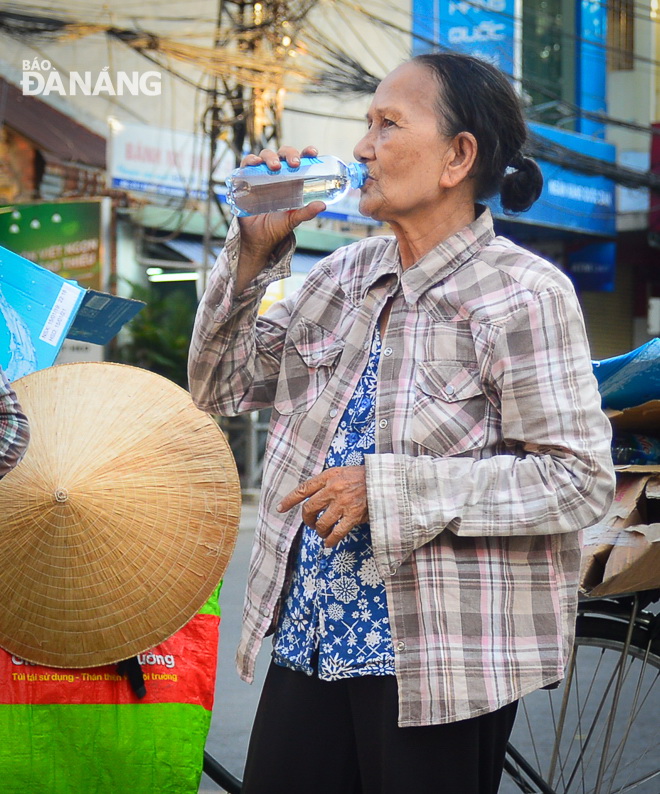 An elderly collector of wasted materials drinking water 
