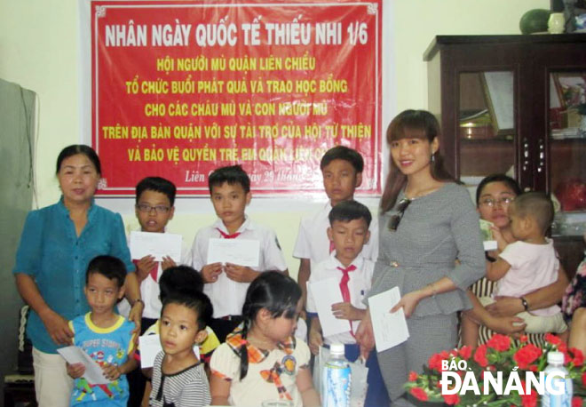 Bà Nguyễn Thị A (trái), Chủ tịch Hội Từ thiện và Bảo vệ quyền trẻ em quận Liên Chiểu cùng nhà tài trợ trao quà nhân Ngày Quốc tế Thiếu nhi 1-6 cho trẻ em trên địa bàn quận.