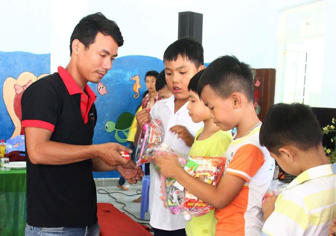 Anh Ngô Văn Trị (trái) trao quà cho các em nhỏ tại Trung tâm Bảo trợ nạn nhân chất độc da cam và trẻ em bất hạnh Đà Nẵng.  (Ảnh nhân vật cung cấp)