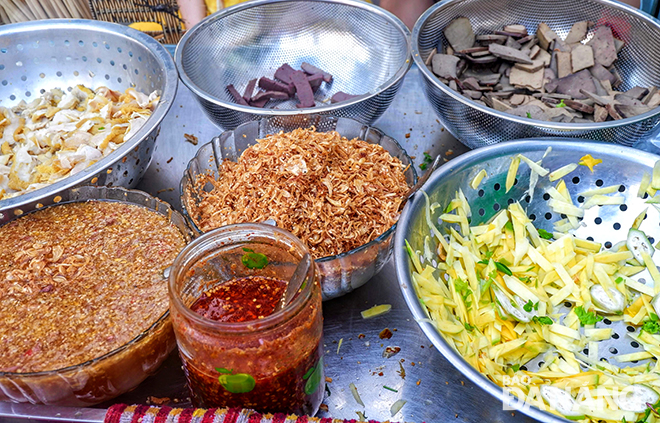 Some ingredients used for the delicious mixture, including sliced beef organs, thinly-sliced green mango and unripe bananas, and ginger fish sauce.