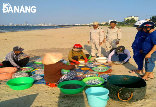 Lực lượng quy tắc đô thị vận động người dân sau khi phân loại cá mang vào chợ bán thay vì buôn bán trên vỉa hè đường Nguyễn Tất Thành.