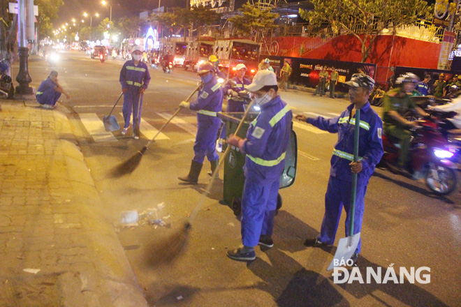 Công nhân môi trường tiến hành thu gom rác trên đường Trần Hưng Đạo .