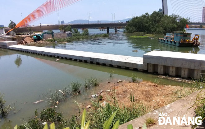Đập ngăn nước thuộc dự án Khu công viên văn hóa và vui chơi giải trí phía đông nam Đài Tưởng niệm của Công ty TNHH Công viên Châu Á làm nước trong hồ Đảo Xanh không chảy ra sông Hàn, ứ đọng gây mùi hôi.