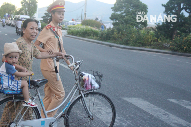 A female traffic police officer helping local residents cross the road safely