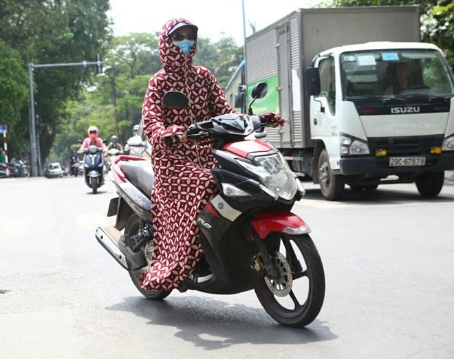 Trang phục bịt kín để chống chọi lại cái nắng gắt của người dân khi tham gia giao thông. (Ảnh: Danh Lam/TTXVN)
