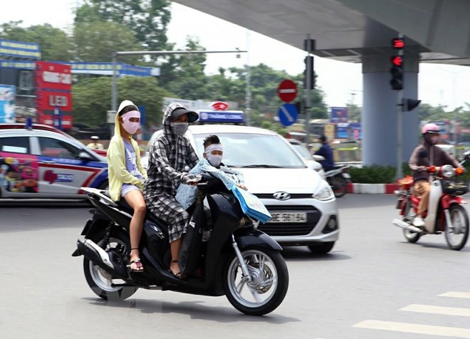 Trang phục bịt kín để chống chọi lại cái nắng gắt của người dân khi tham gia giao thông. (Ảnh: Danh Lam/TTXVN)
