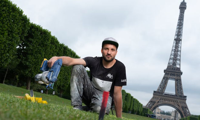 Nghệ sĩ Saype khởi đầu bức họa mới trên bãi cỏ tại Champs de Mars, Paris.
