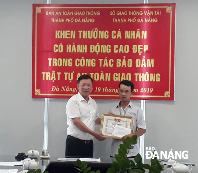 Director of the municipal Department of Transport Le Van Trung (left) giving a Certificate of Merit to Mr Hung