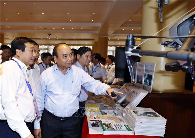 Thủ tướng Nguyễn Xuân Phúc và các đại biểu tham quan triển lãm công nghệ phòng chống thiên tai được trưng bày tại hội nghị. Ảnh: Thống Nhất/TTXVN